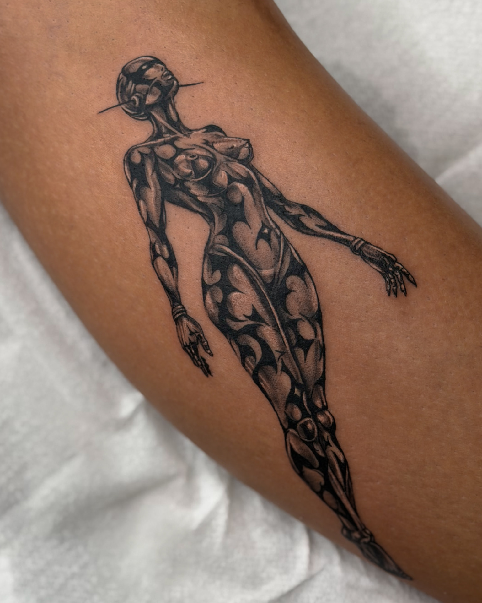 Chrome female figure tattoo on a leg